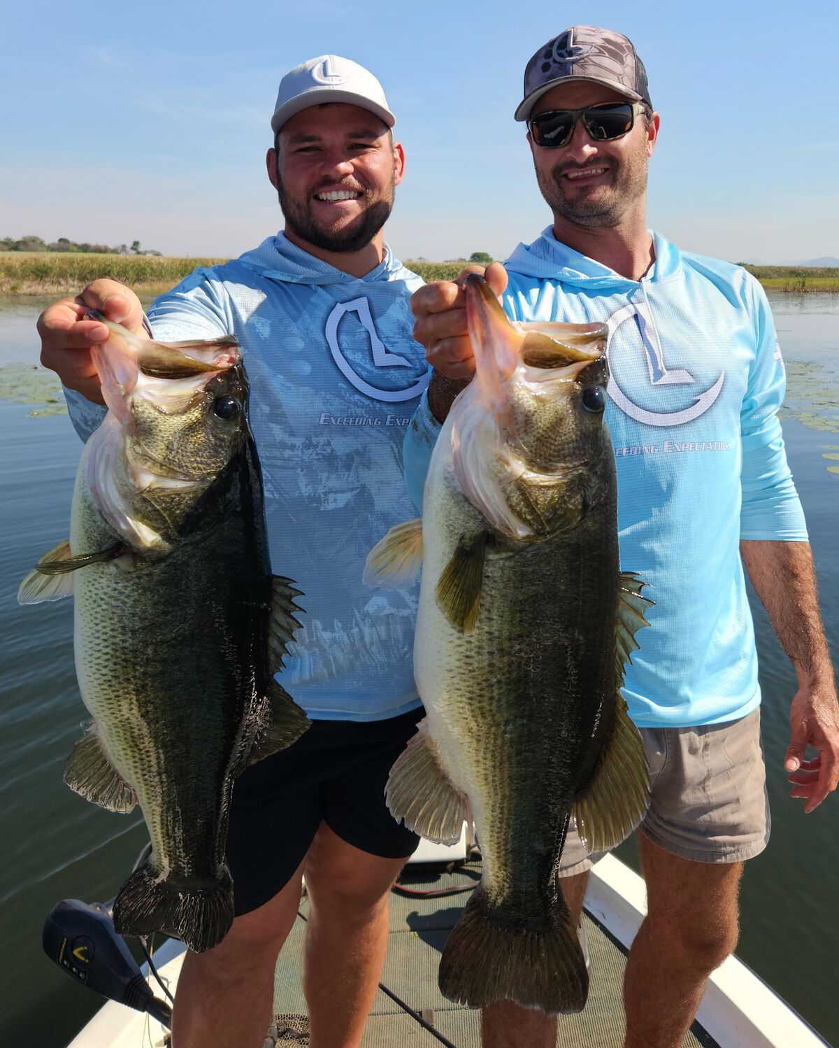 Two anglers each holding a trophy largemouth bass