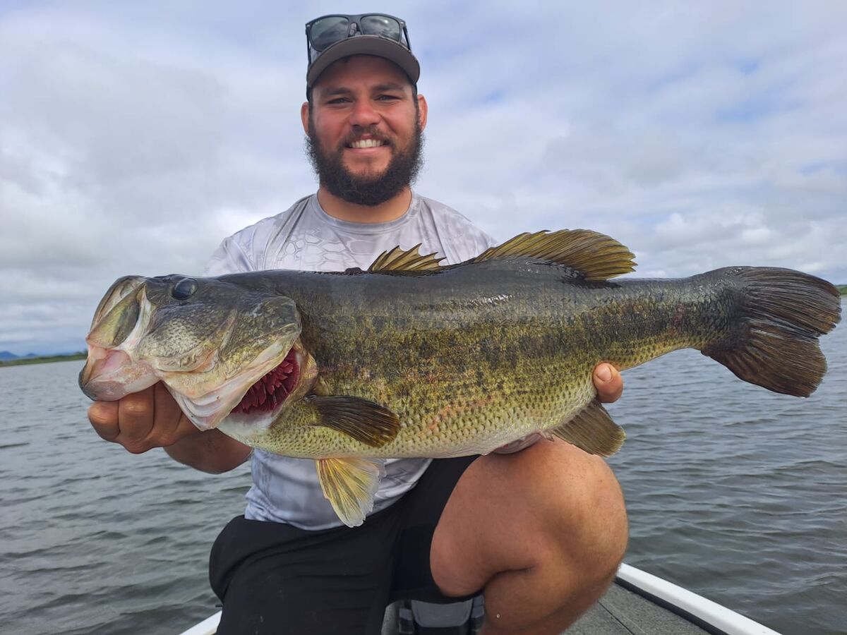 Angler holding a trophy largemouth bass on a freshwater trip