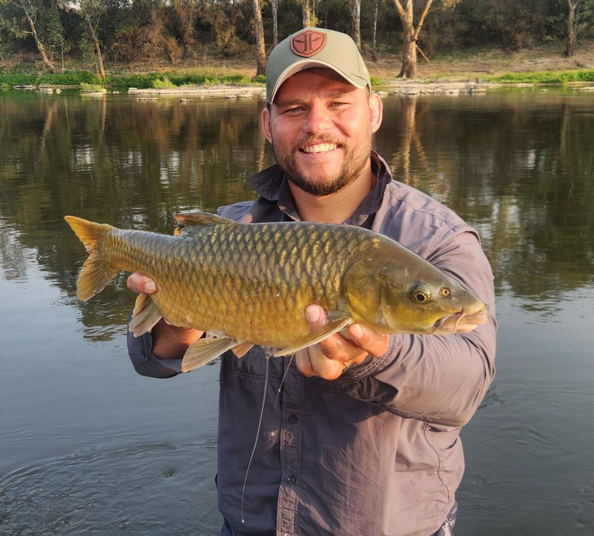 Angler holding a carp on the riverbank