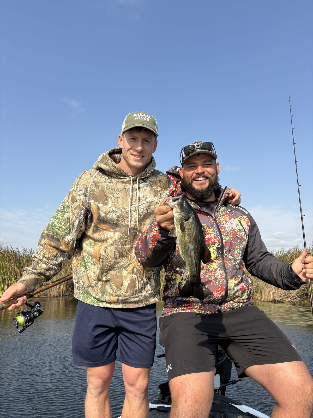 WildTide founders Chris and Conraad on a boat, holding a largemouth bass