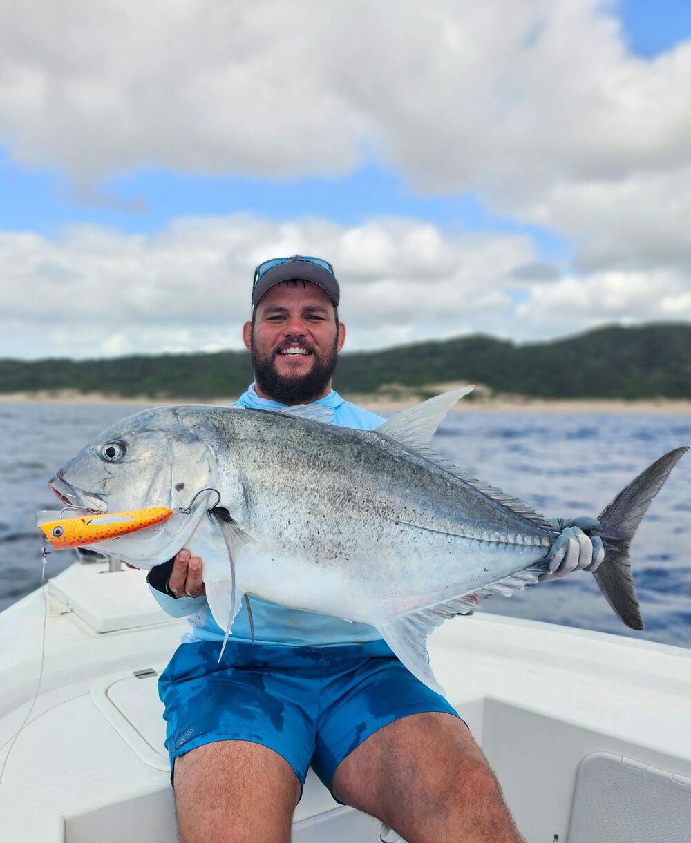 Angler holding a giant trevally on an offshore charter