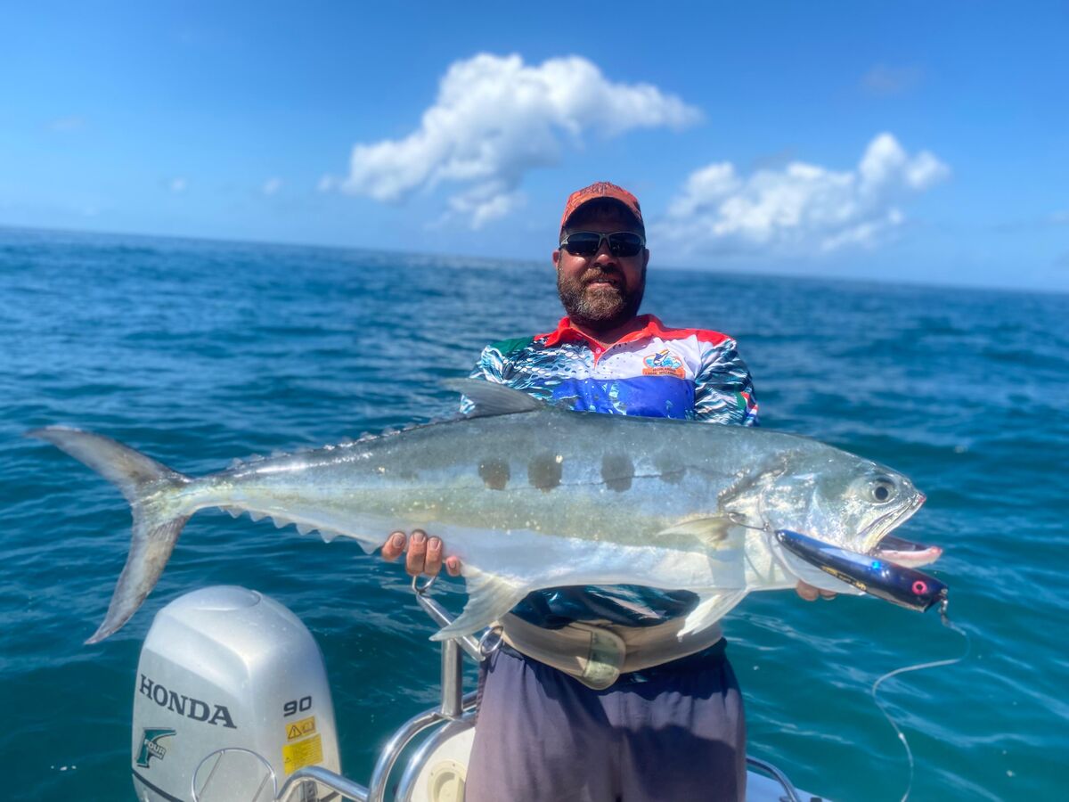 Angler holding a queenfish offshore