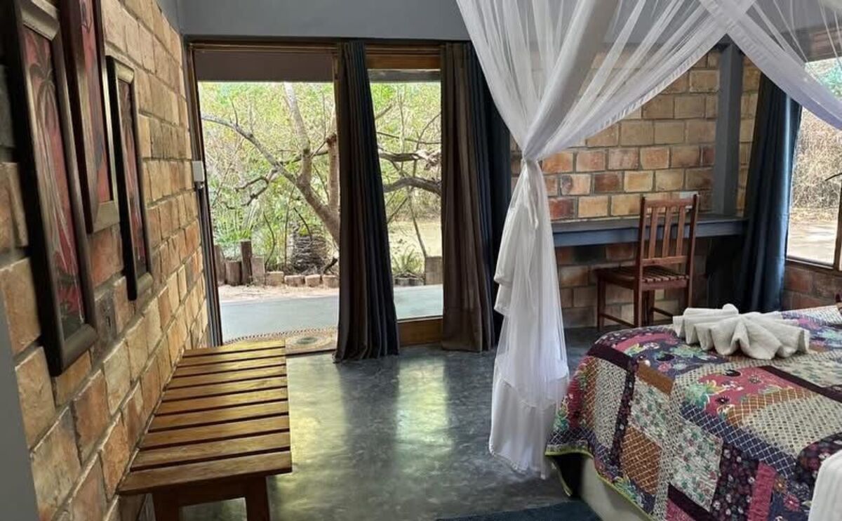 Bedroom with mosquito-net canopy and doors opening onto the garden