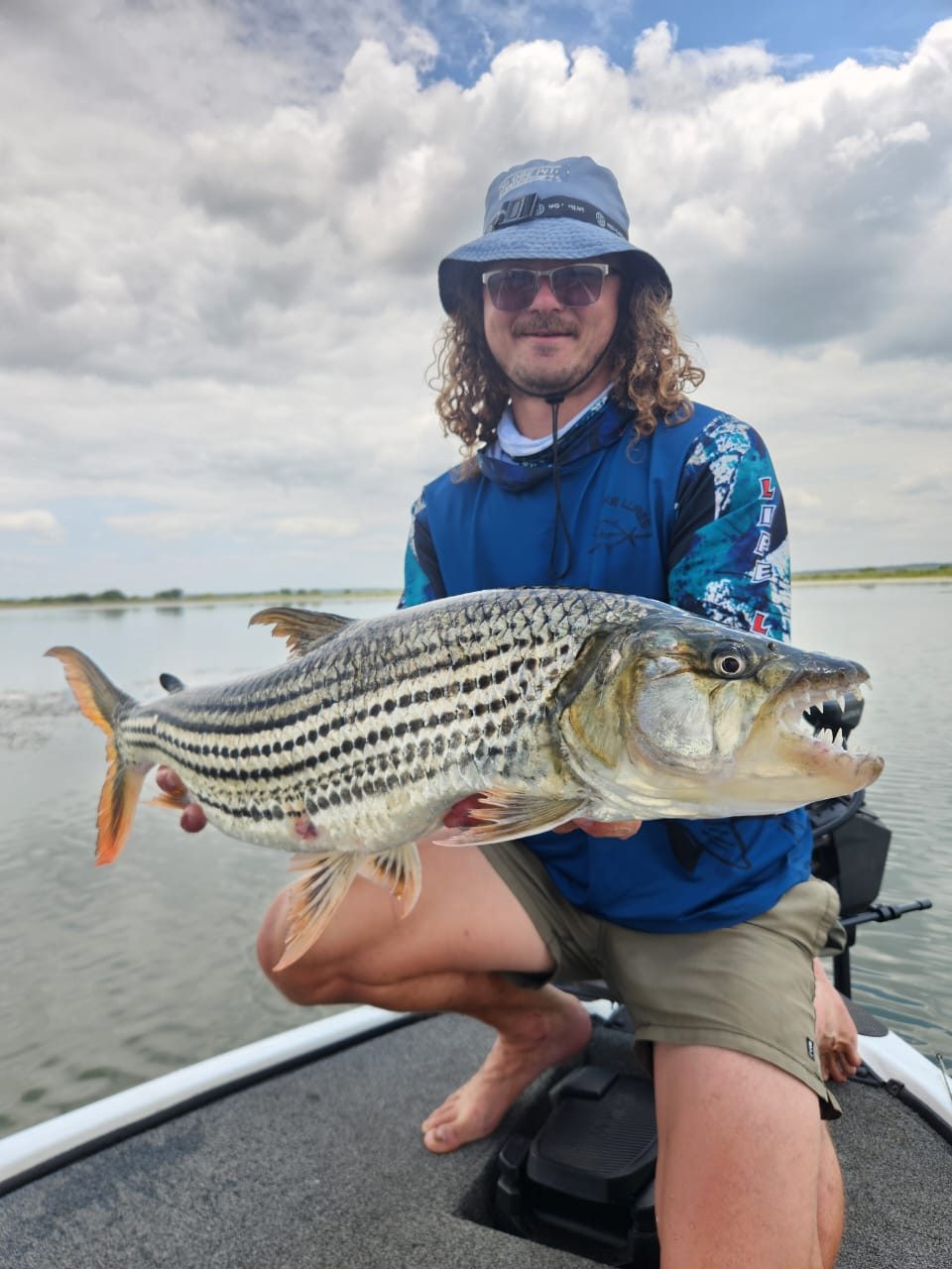 Angler holding a big tigerfish with its striped flanks and teeth on show